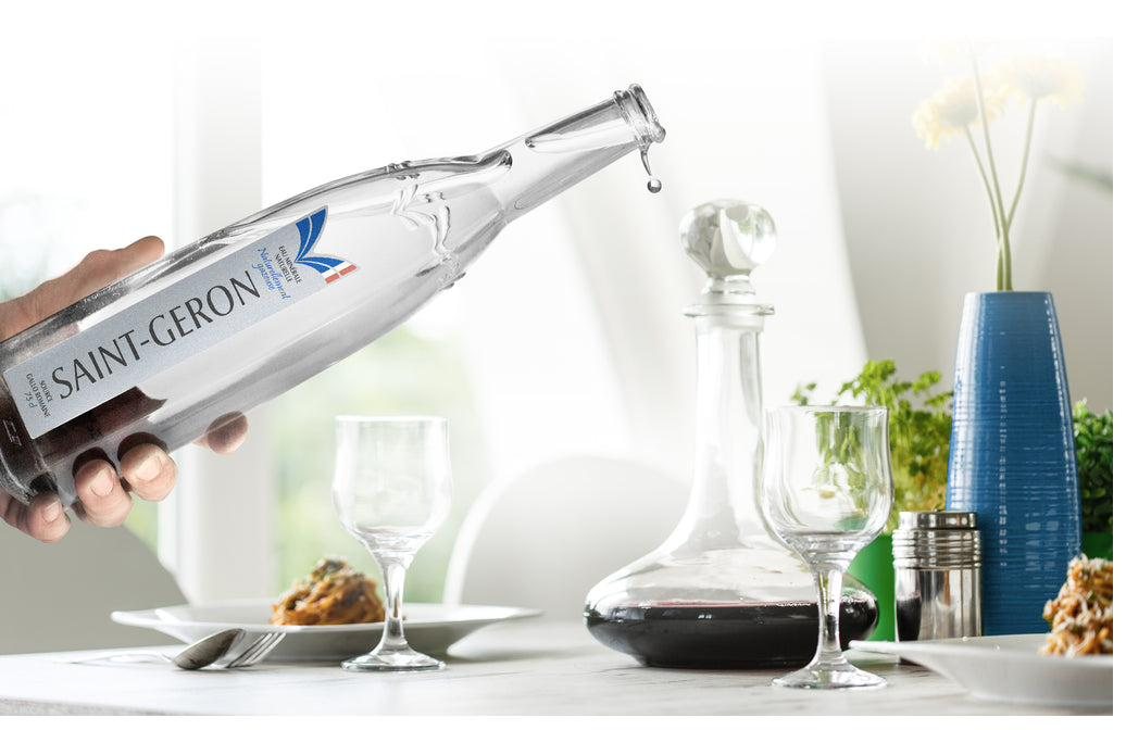 Saint-Géron being poured at a set dining table with a decanter and glasses